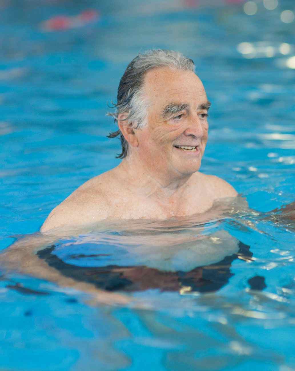 Elderly man floating in pool