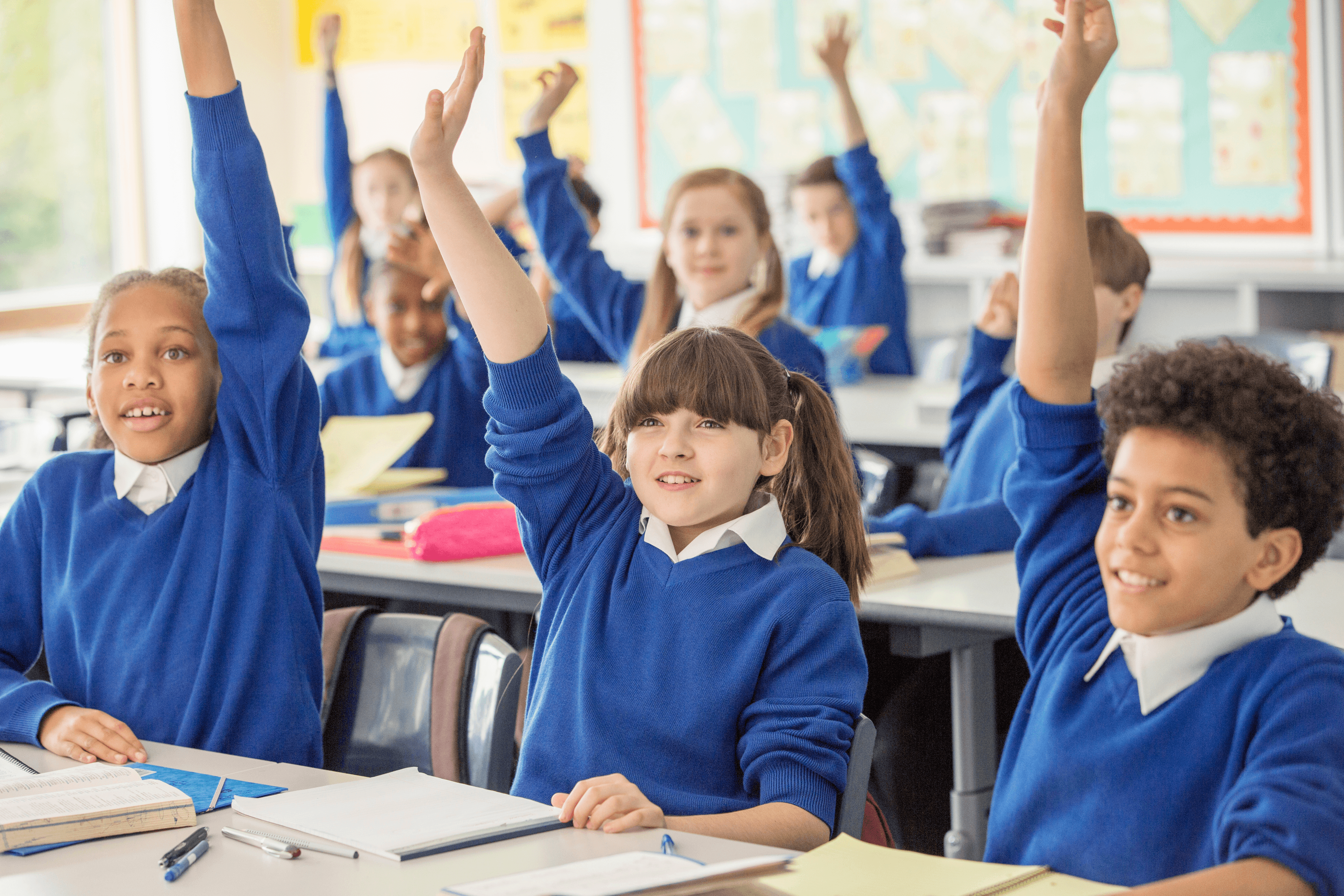Kids with hands raised in classroom