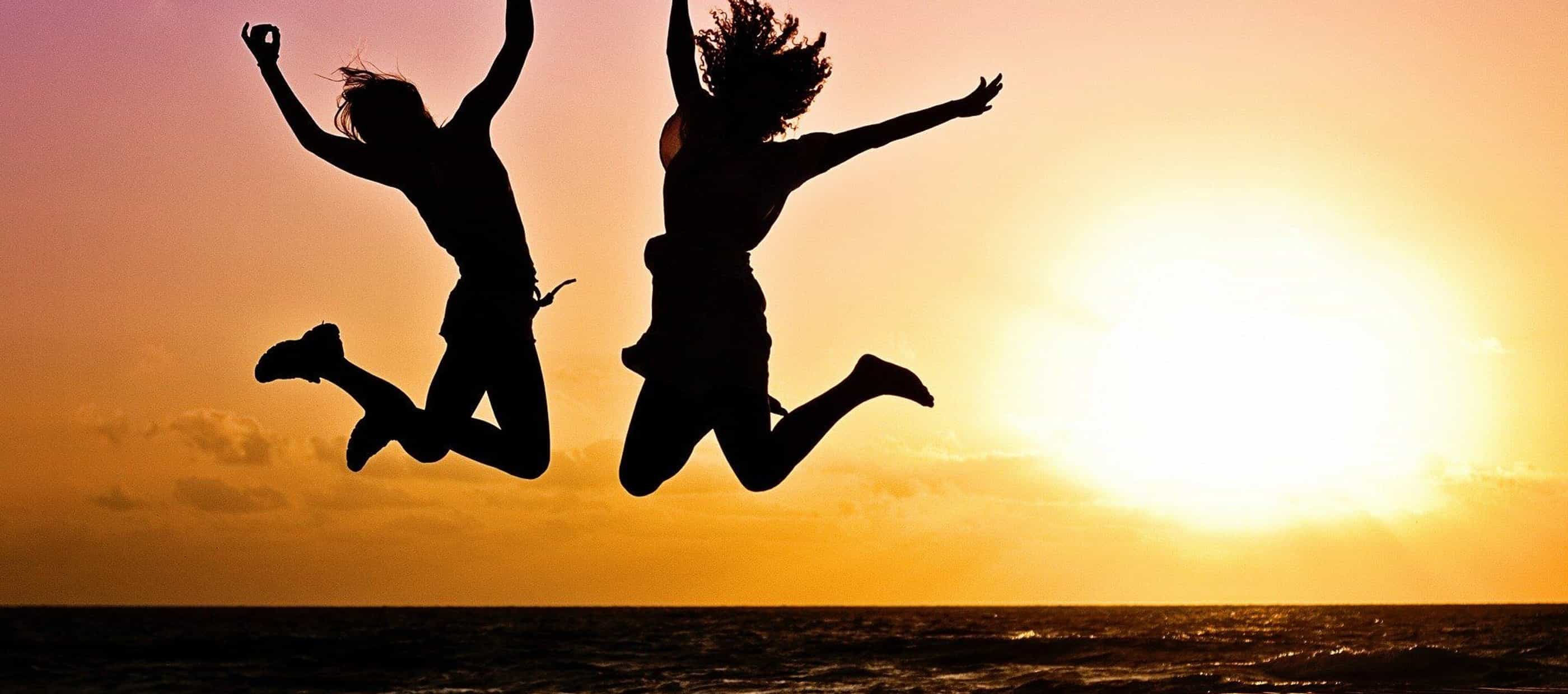 Silhouettes jumping against a setting sun background