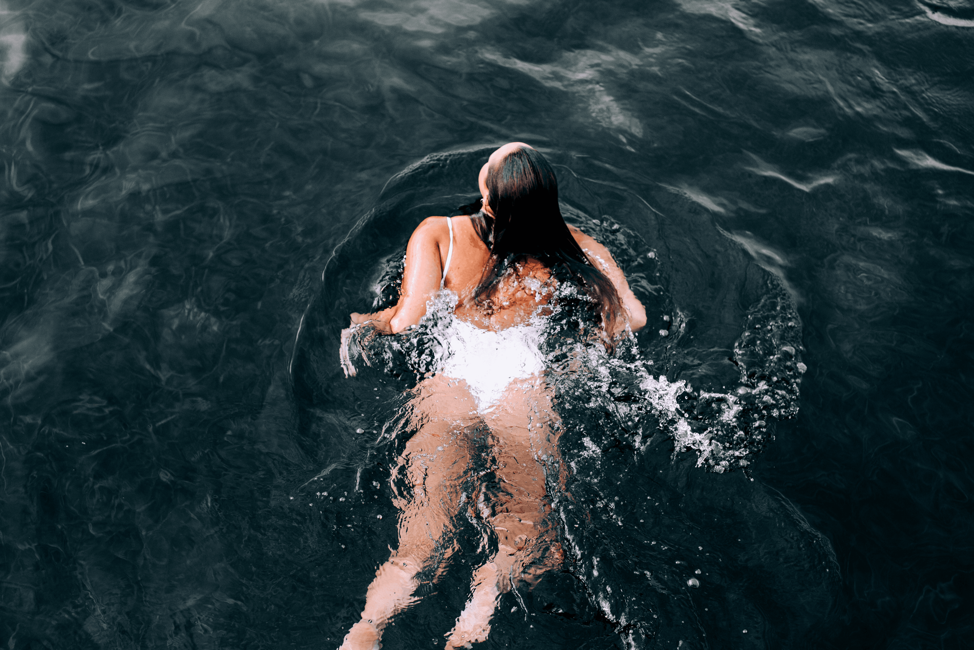 Woman in white costume swimming in lake