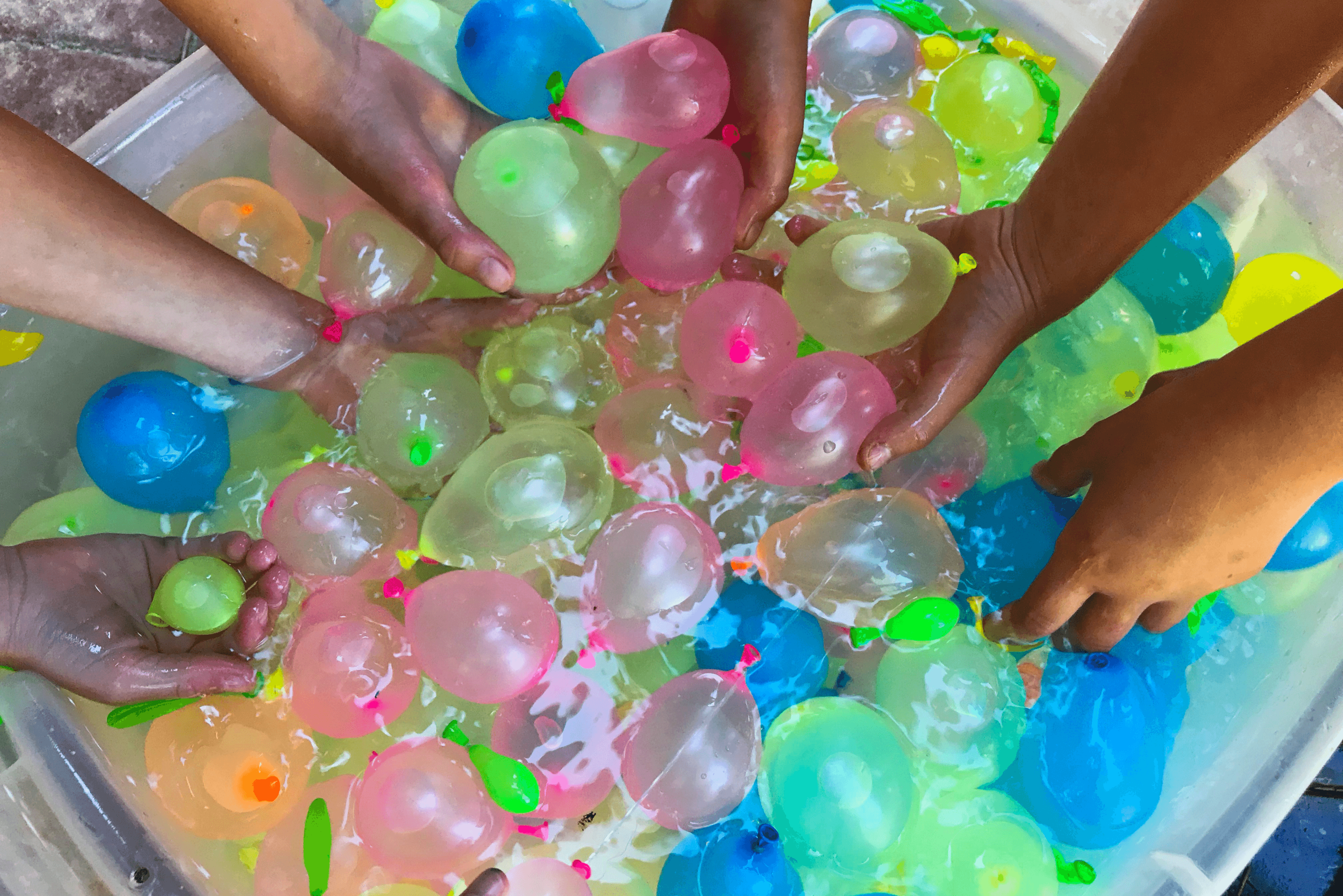 Kids hands grabbing water balloons