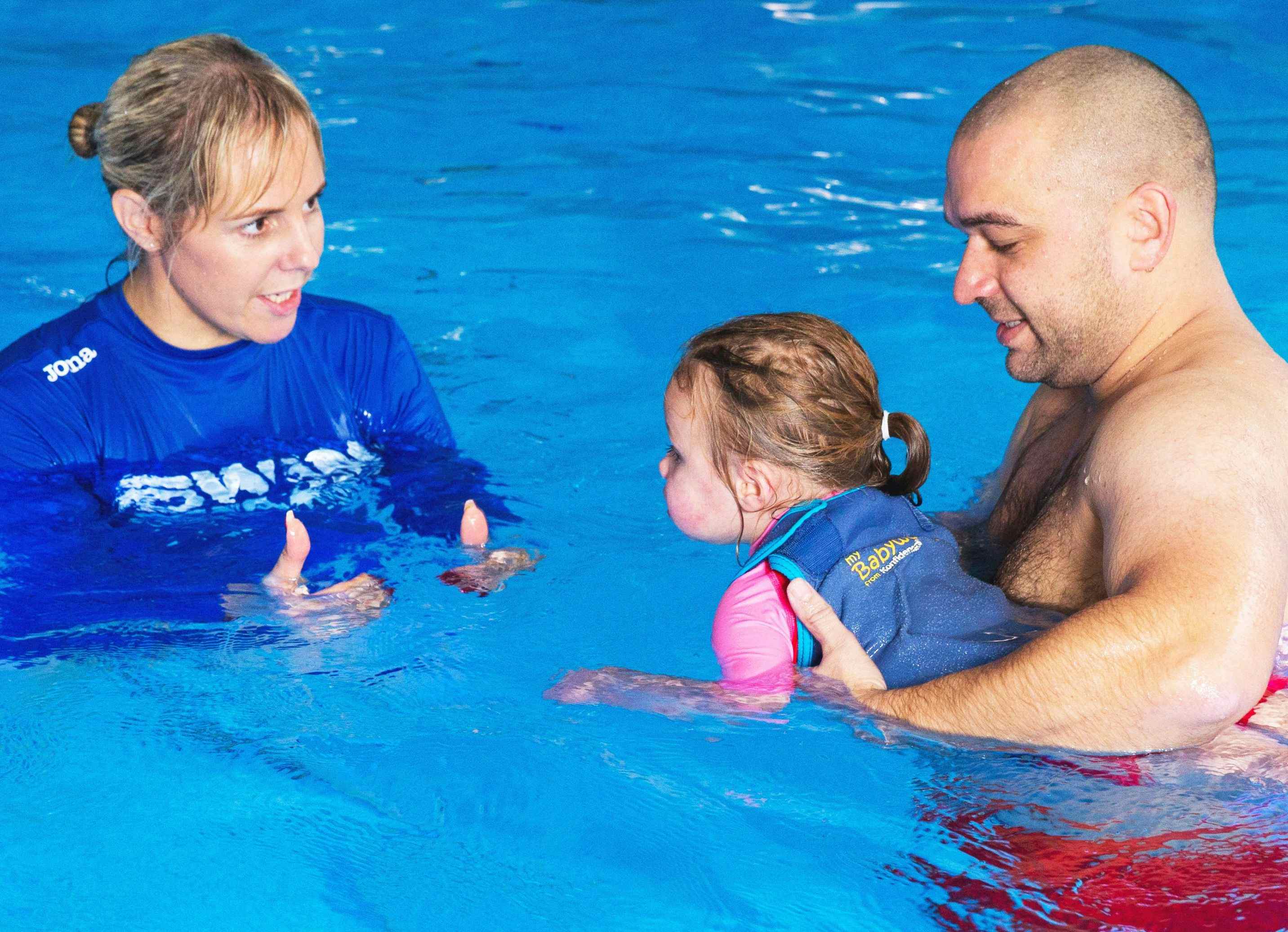 Father supporting child in swimming pool
