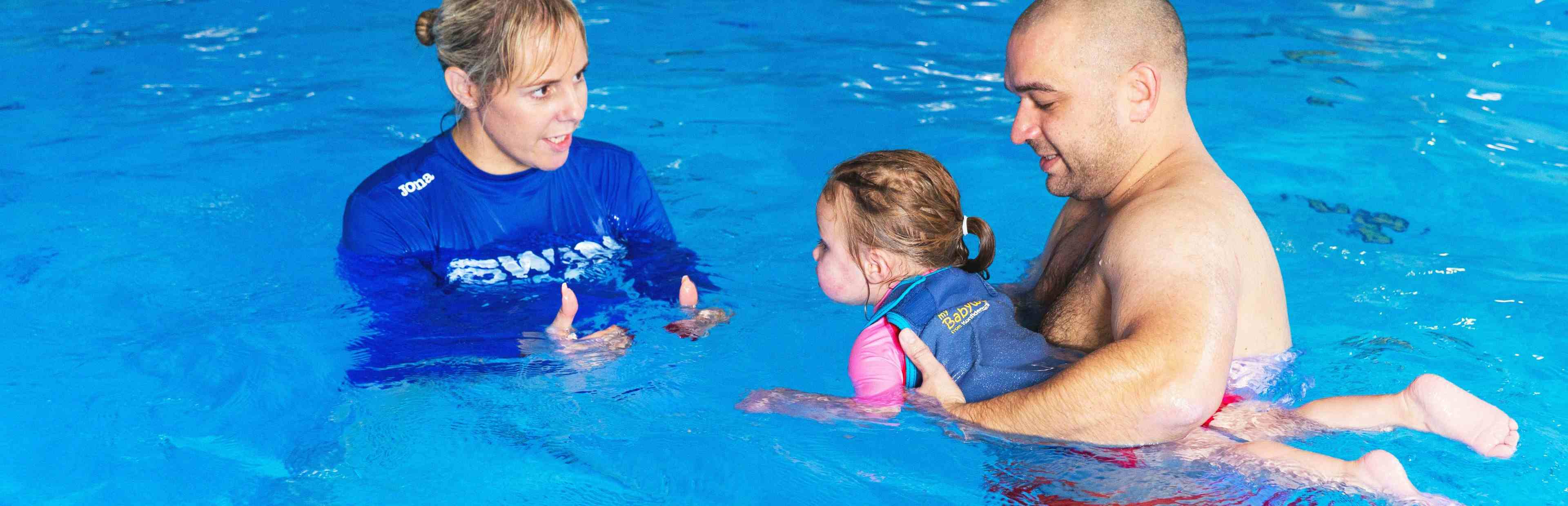 Father supporting child in swimming pool