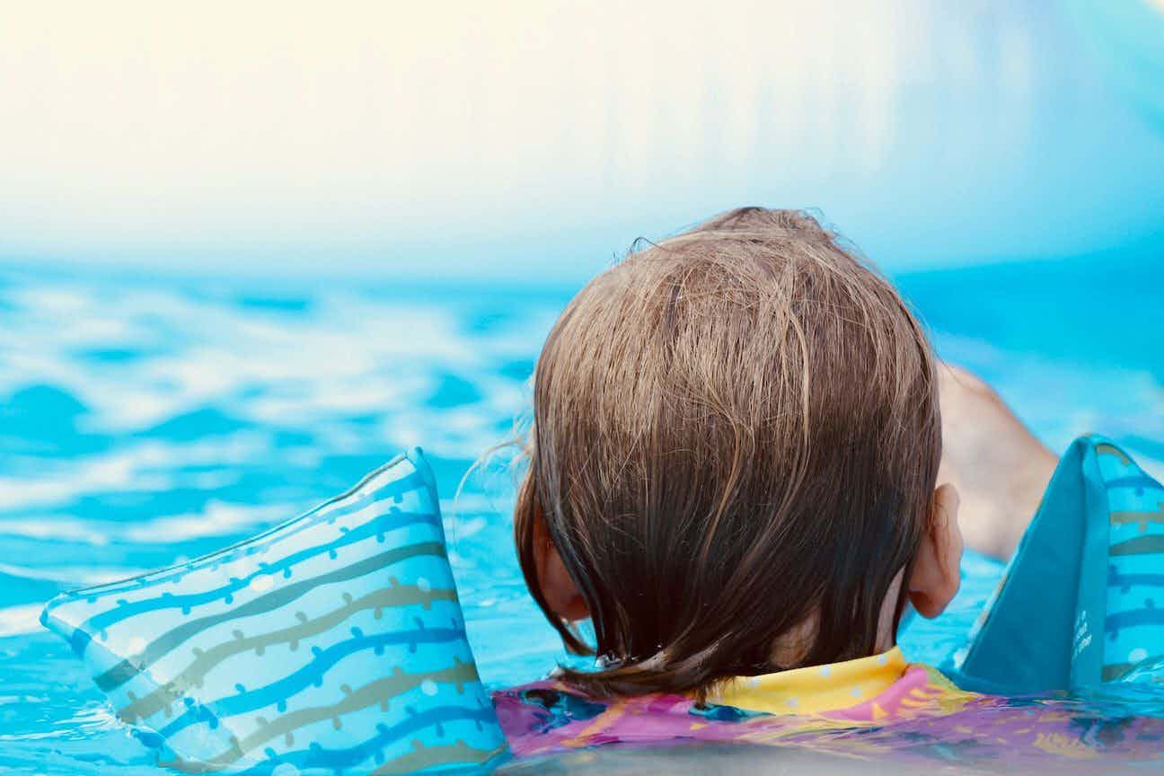 Child swimming and wearing floaties