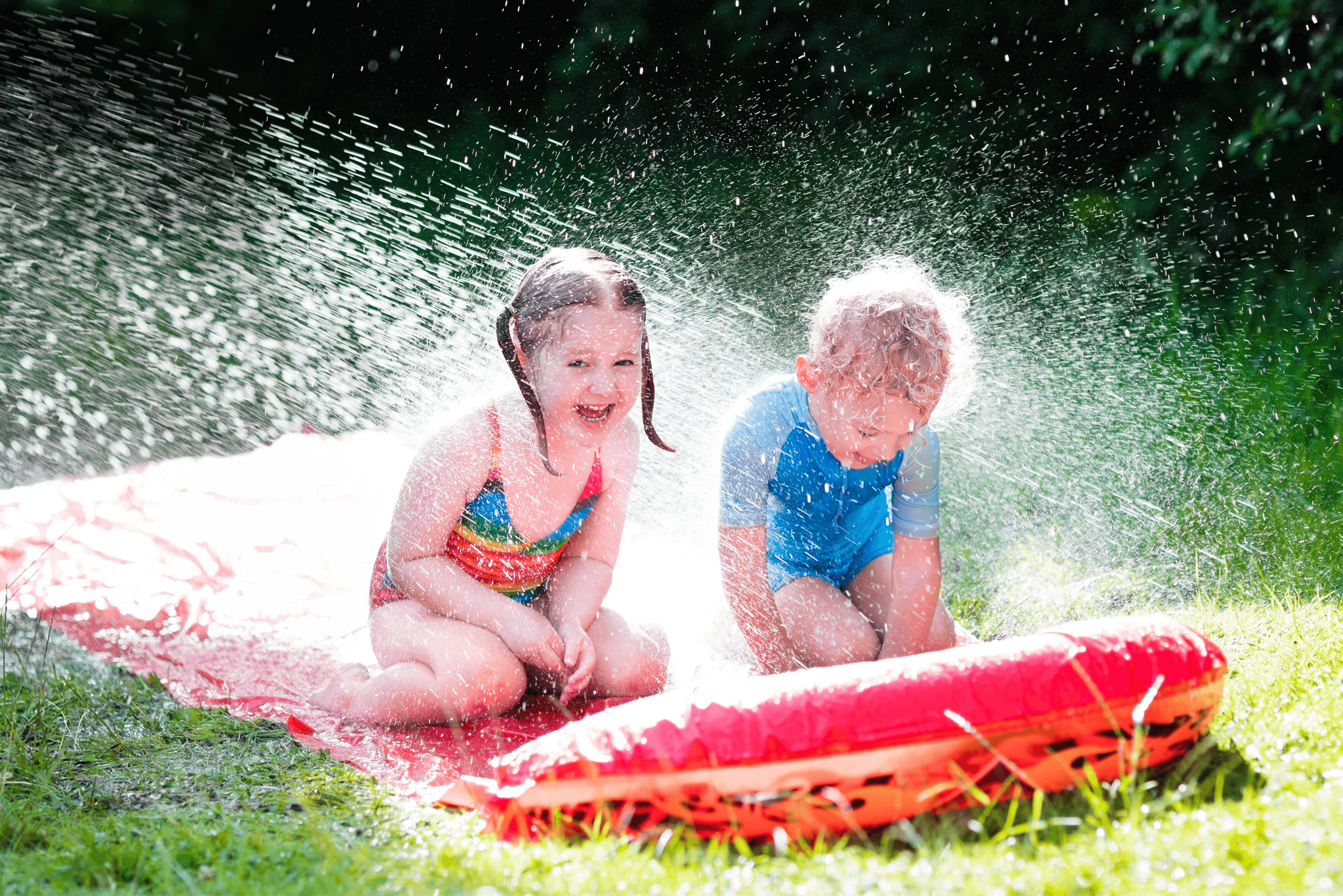 Kids playing on inflatable slip 'n' slide in garden