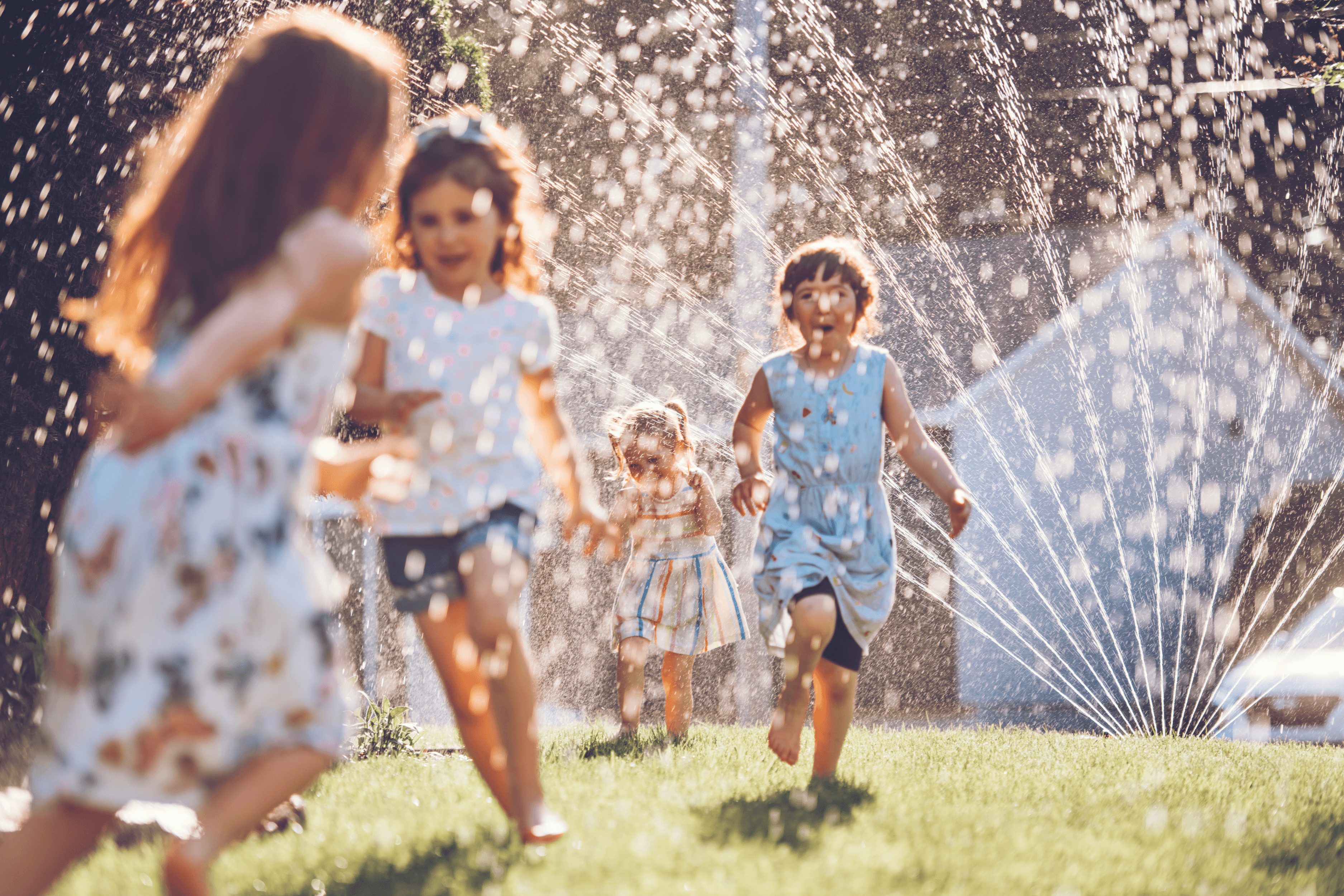 Kids playing with sprinkler in garden