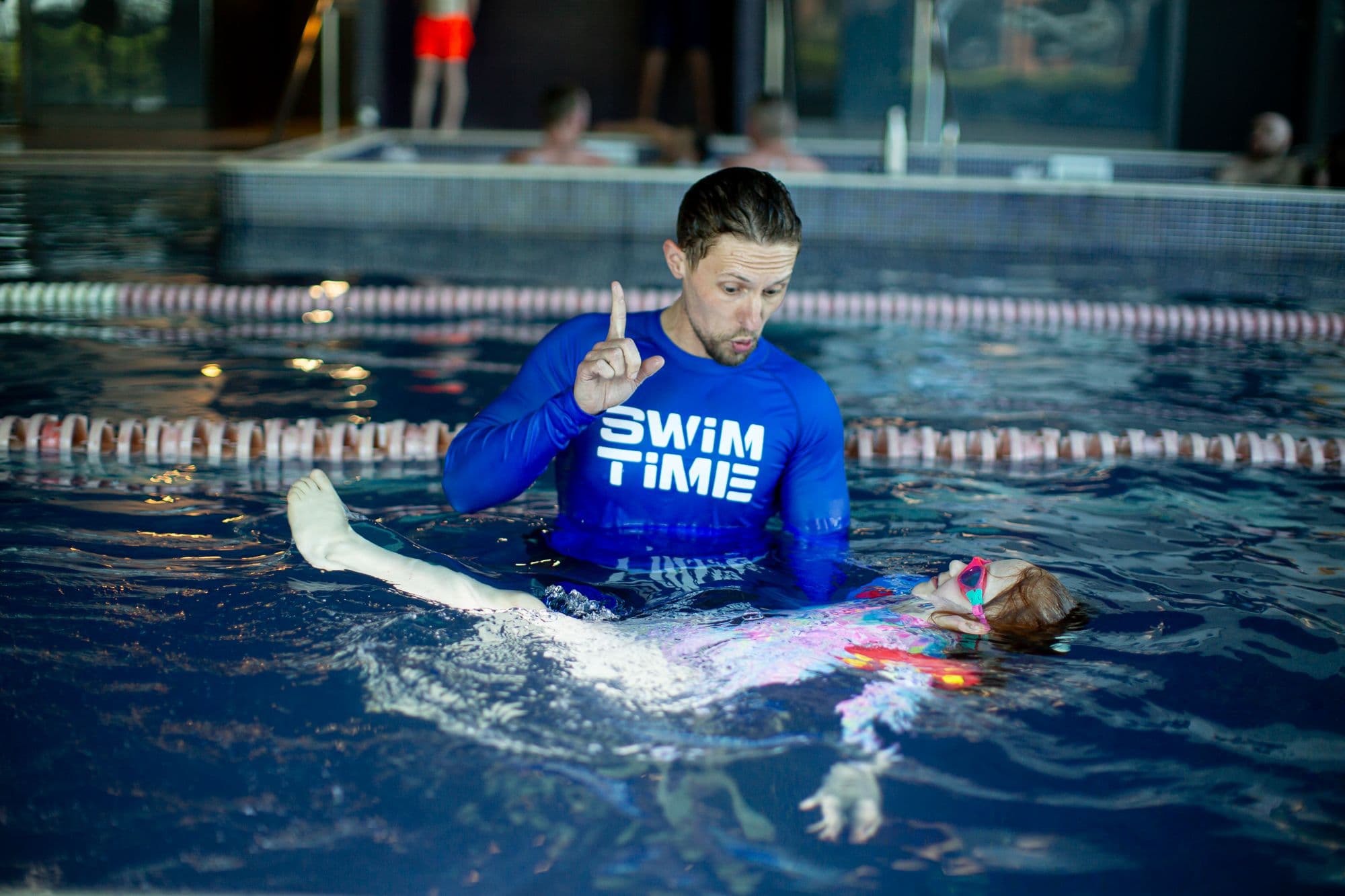 Swimming instructor supporting child.