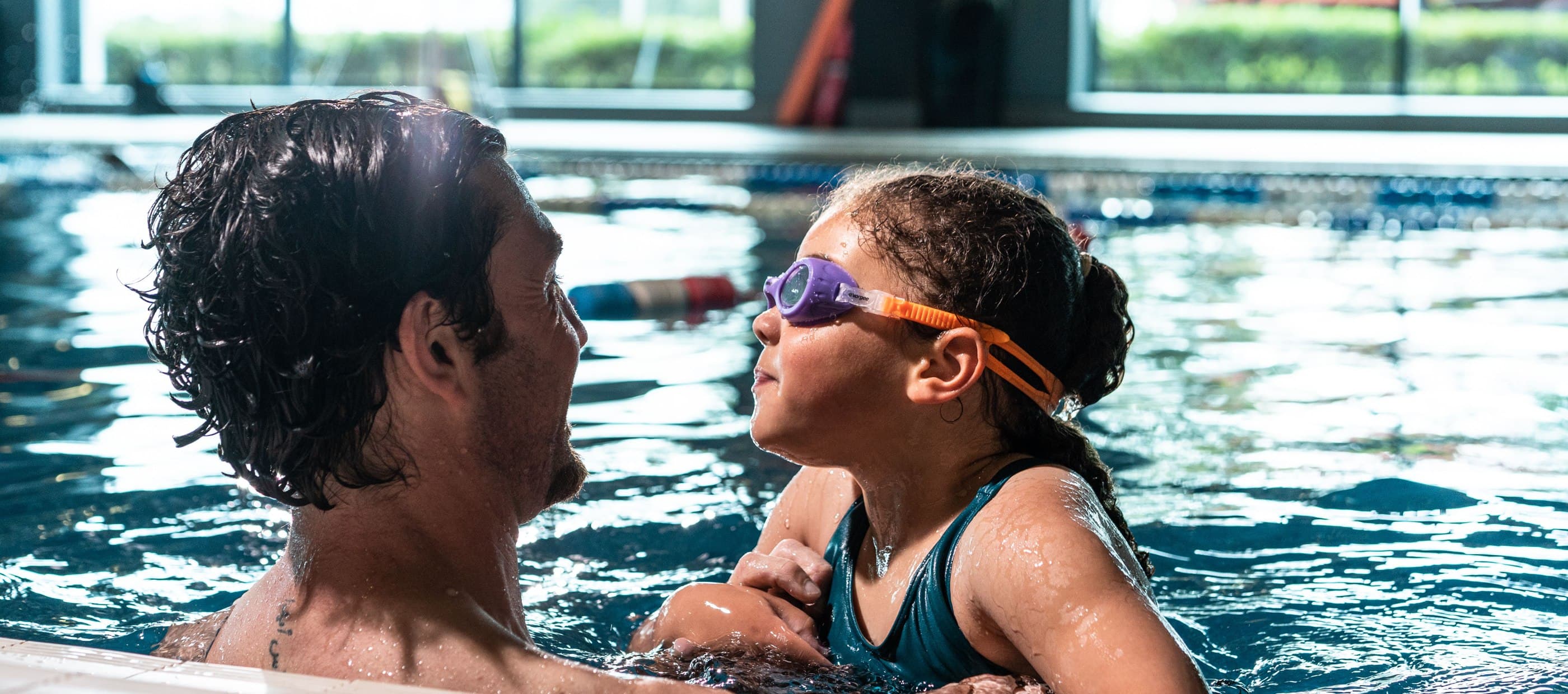 Father supporting child in swimming pool