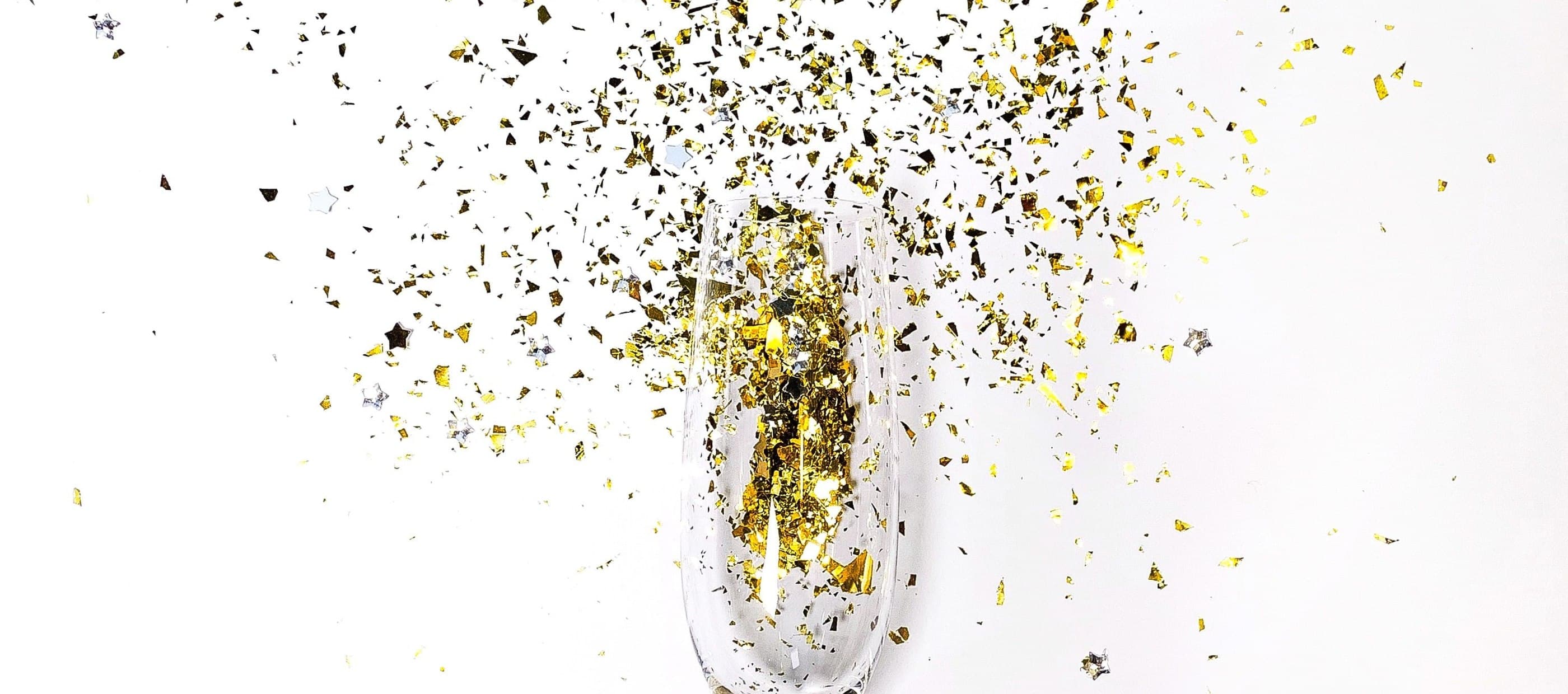 Gold confetti exploding out of champagne glass
